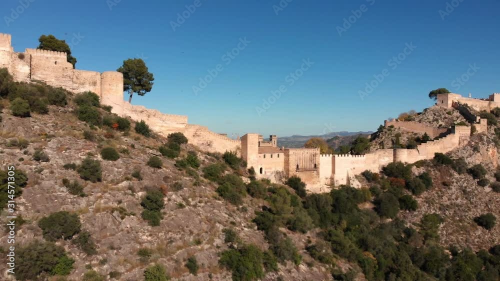 Aerial fly towards an old medieval castle on a v shaped rocky mountain from a close distance Aerial fly towards an old medieval castle on a v shaped rocky mountain from a close distance