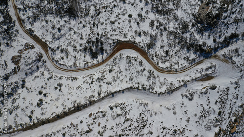 Aerial drone view of curvy road in beautiful snowed mountain in winter © aerial-drone