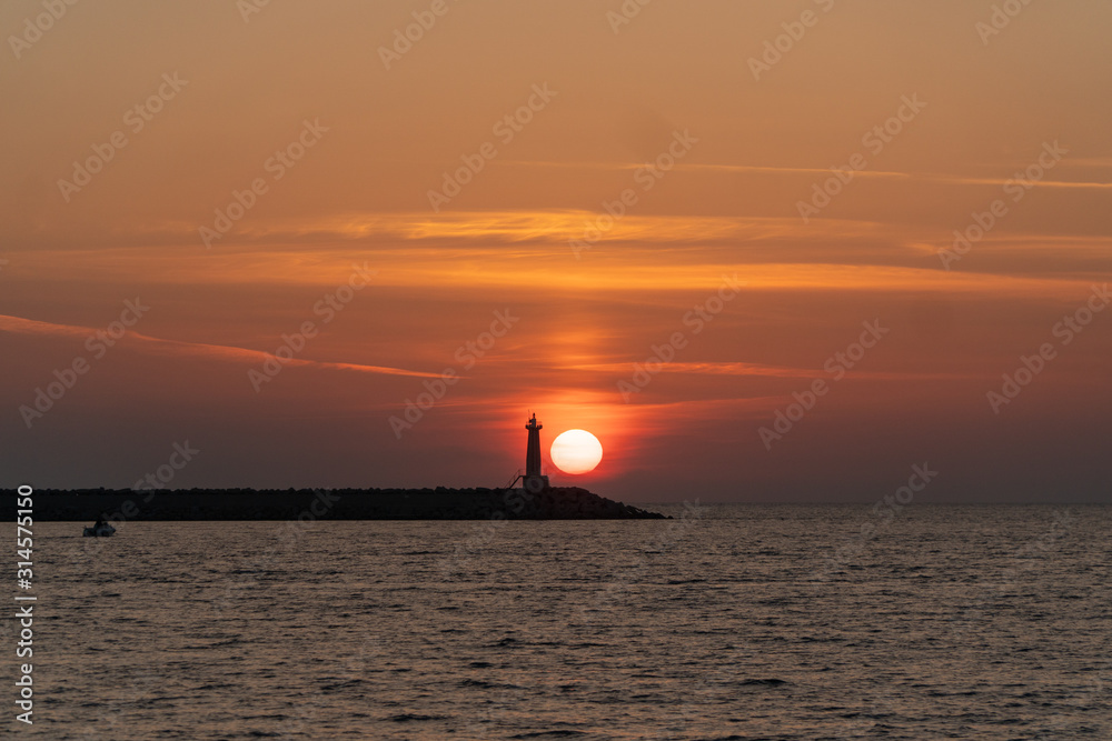 Silhouette of a lighthouse on the horizon in the rays of the setting sun Silhouette of a lighthouse on the horizon in the rays of the setting sun