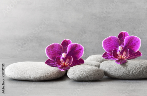 Spa stones and orchid flower on the grey background