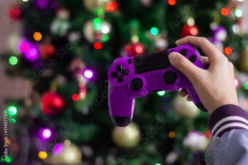 Woman's hand with a video game control with Christmas lights background and copy space. Christmas fun concept.