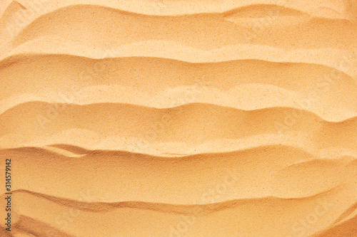The beach background. Sand with wave texture. Top view with copy space.