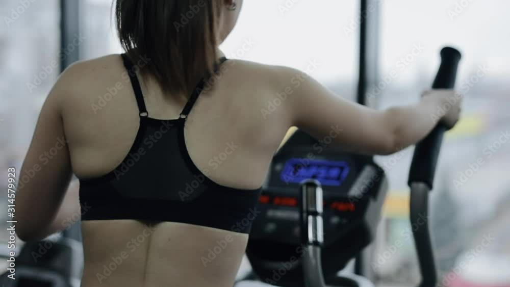 Young woman at the gym riding on spinning bike. Cycling on bicycle machine. Young woman at the gym riding on spinning bike. Cycling on bicycle machine.
