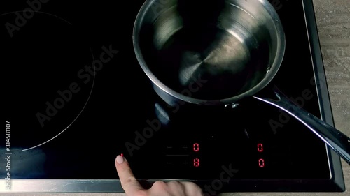 Setting water on a flat electric stove with a timer set, closeup  photo