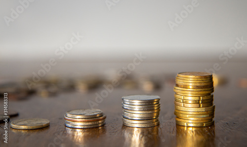 Stacks of silver and brass coins on wooden table, pile of coins in the background, white background, money growth concept