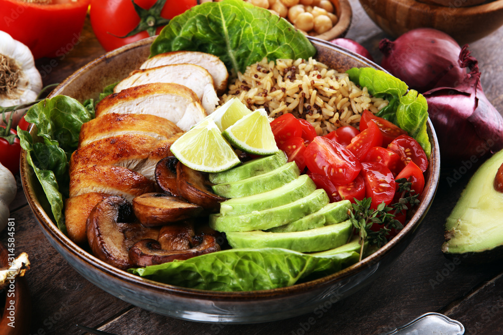 Healthy salad bowl with quinoa, tomatoes, chicken, avocado, lime and mixed greens and mushrooms