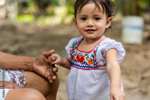 Portrait of a cute child wearing a traditional mexican dress holding her grandmother's hand