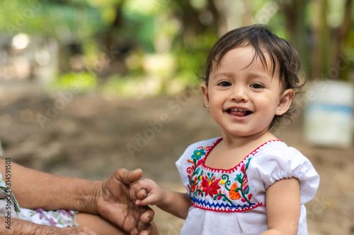 Portrait of a cute child wearing a traditional mexican dress with her grandmother