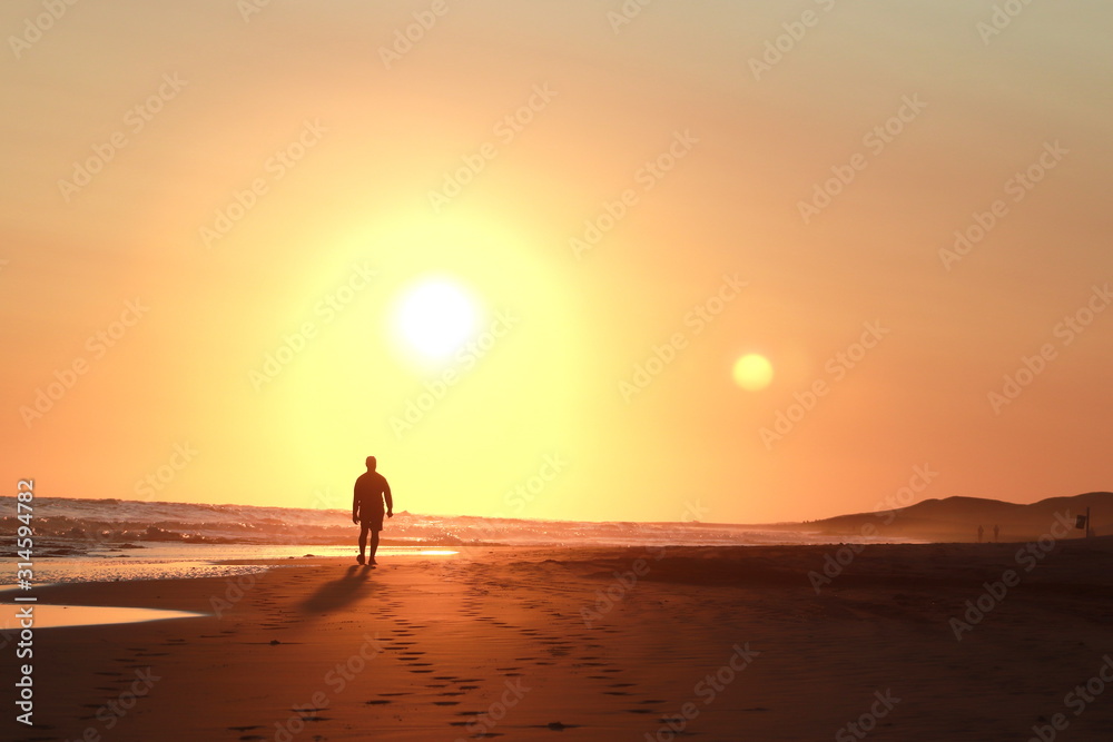 persona caminando al atardecer con el sol de fondo Stock Photo | Adobe
