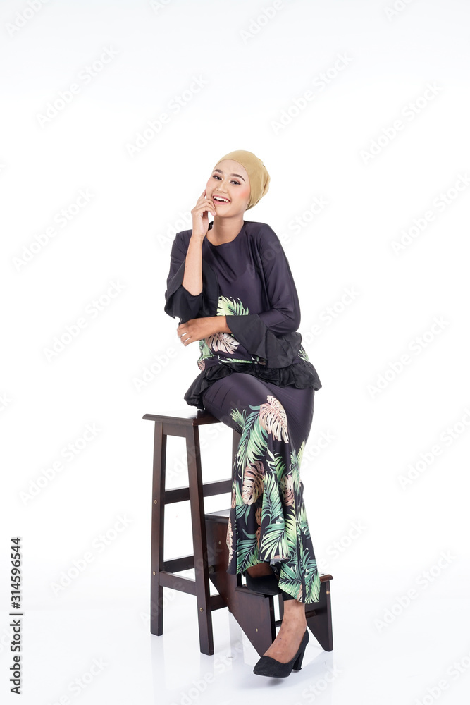 Fototapeta premium Beautiful female model wearing modern kurung, a modern urban lifestyle apparel for Muslim women isolated on white background. Beauty and hijab fashion concept.