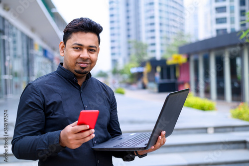 Young entrepreneur or Businessman working on laptop and using smartphone outside the office building.