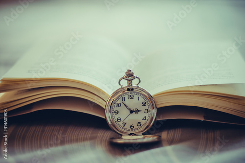 Vintage pocket watch and old book with vintage tone