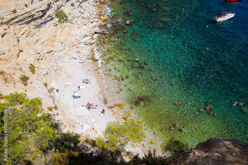 Hidden beach in the Calanques de Marseille with blue waters at the bottom of a cliff