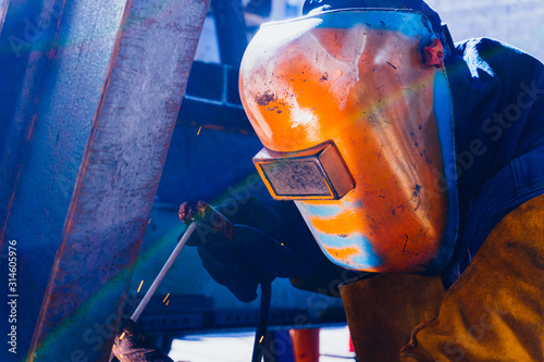 Hombre soldador con el casco puesto soldando metal