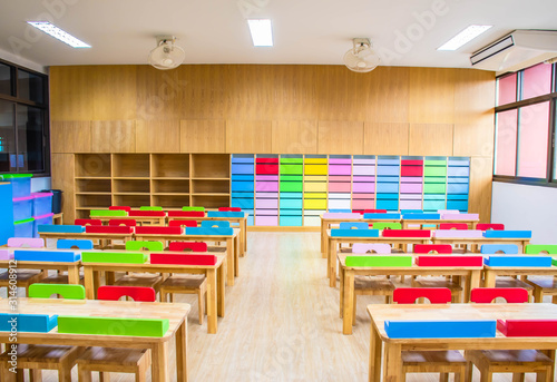 Interior of kindergarten classroom consist desks and chairs.
