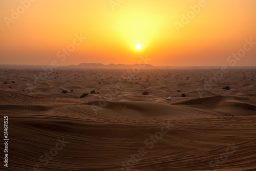 car amidst sand dunes in desert during sunset