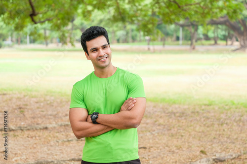 Active man in sportswear stretching one in the park, front view