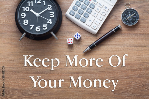 Fényképezés Keep more of your money written on wooden table with clock,dice,calculator pen a