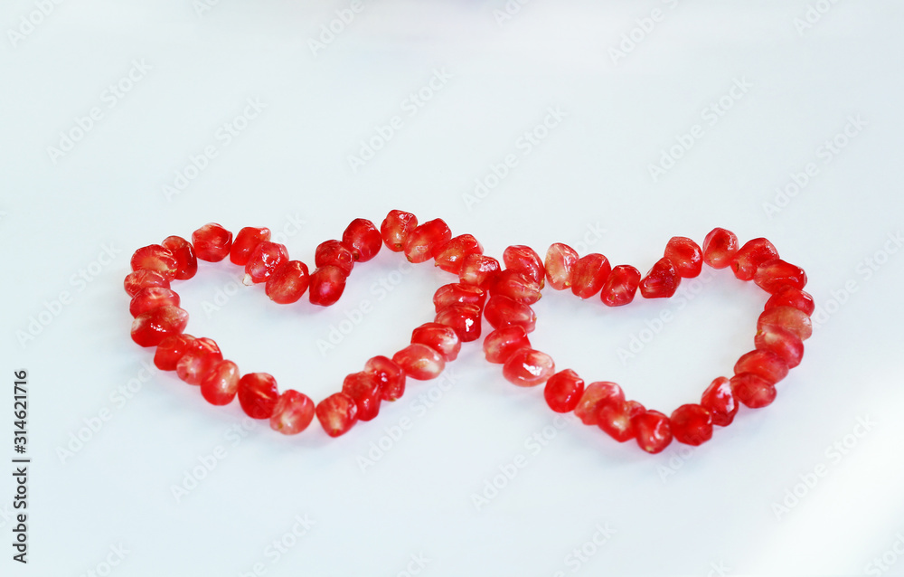 Heart shaped red pomegranate seed on a white background.
