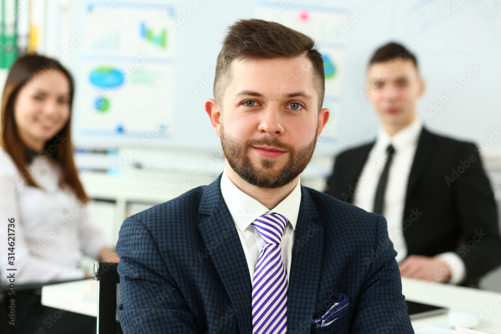 Focus on smart male working in big modern building and discussing important business strategy with younger colleagues and employees. Company meeting concept. Blurred background Focus on smart male working in big modern building and discussing important business strategy with younger colleagues and employees. Company meeting concept. Blurred background