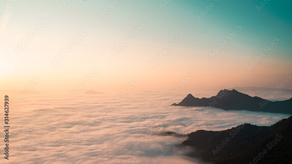 The sunrise above the clouds surrounding by the mountains, Top view.