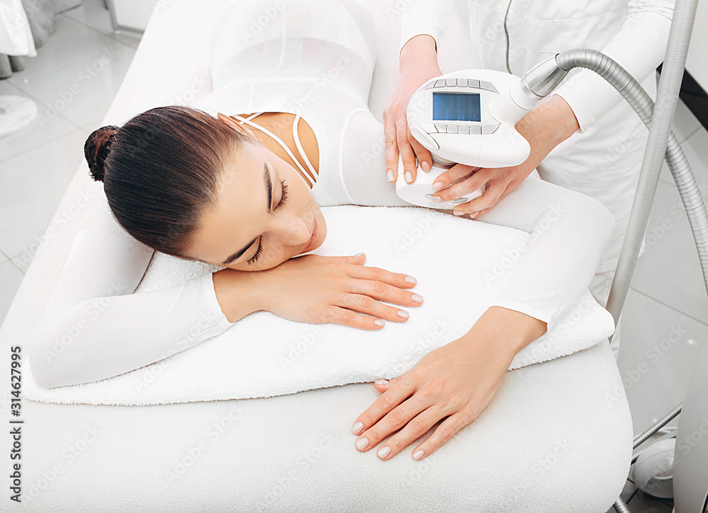 Beautician doing LPG massage on the hand of a beautiful woman. Removing sagging skin on the arm and removing cilulitis Beautician doing LPG massage on the hand of a beautiful woman. Removing sagging skin on the arm and removing cilulitis