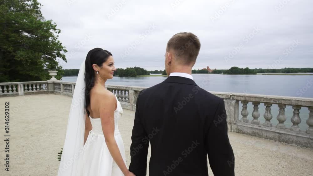Married young couple walking together back view, later looking at each other camera follows Married young couple walking together back view, later looking at each other camera follows