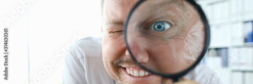 Smiling businessman hold magnifying glass in hand. Where to invest profit search concept photo