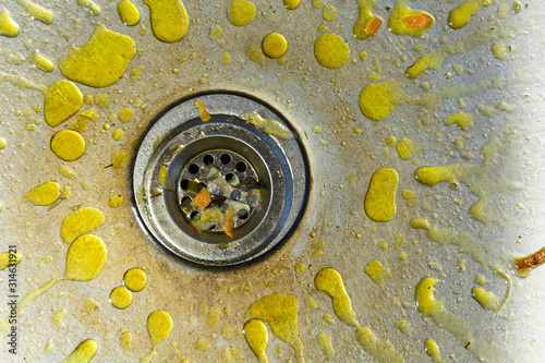 A dirty and littered sink with yellow grease stains.