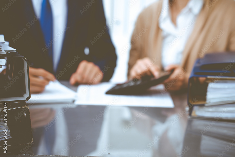 Binders with papers waiting to be processed with businessman or bookkeeper back in blur. Accounting planning budget. Audit, insurance and business concept Binders with papers waiting to be processed with businessman or bookkeeper back in blur. Accounting planning budget. Audit, insurance and business concept