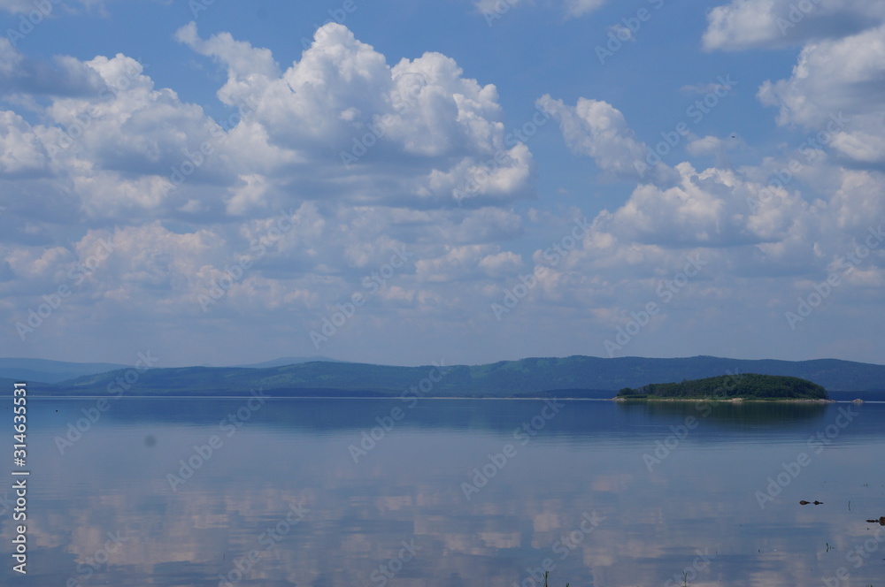Clouds reflected in the lake. Landscape with mountains, sky and a pond. Natural background.