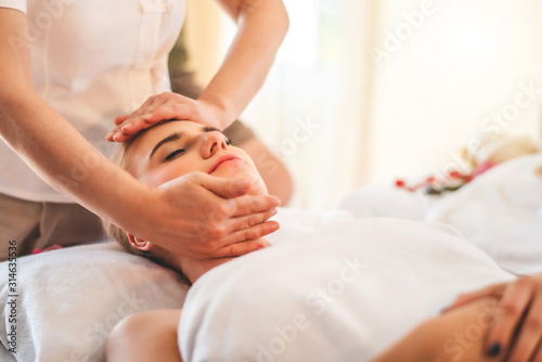 Beautiful young attractive Caucasian woman having head massage by Thai Masseur in spa salon. Beauty treatment and body care concept.