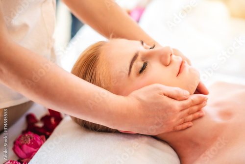 Beautiful young attractive Caucasian woman having head massage by Thai Masseur in spa salon. Beauty treatment and body care concept.