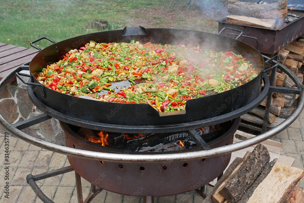 A lot of various sliced vegetables are fried in big steel pan A lot of various sliced vegetables are fried in big steel pan
