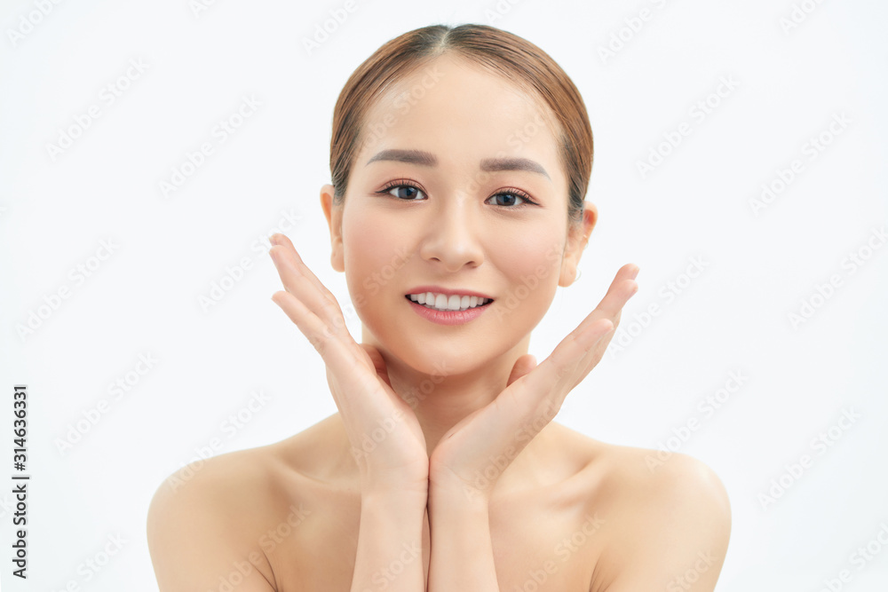 Beautiful young Asian woman with fresh clean skin that touches her face with both hands. Spa, cosmetology and beauty.