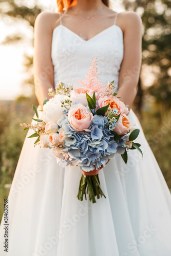 Bride at sunset holding a wedding bouquet in her hands