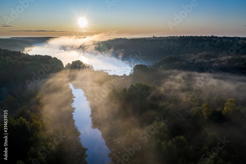 Mist over river with rays in autumn, view from above