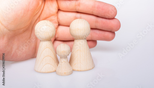 Hand protecting wooden figurines of people as family concept photo