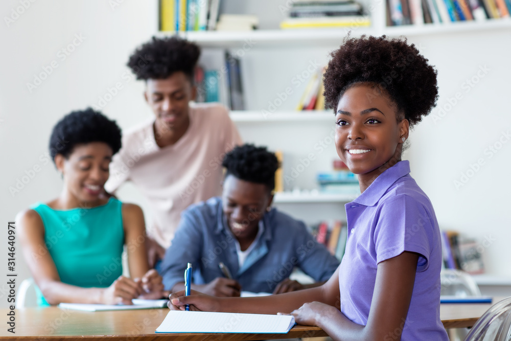 Laughing african american female student learning at desk at school Laughing african american female student learning at desk at school