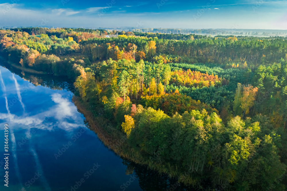 Fototapeta premium Crystal clear lake with chemtrail reflection and forest, aerial view