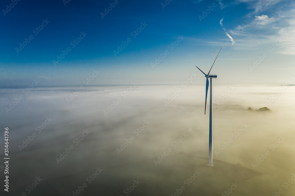 Fog and wind turbines at sunrise in autumn