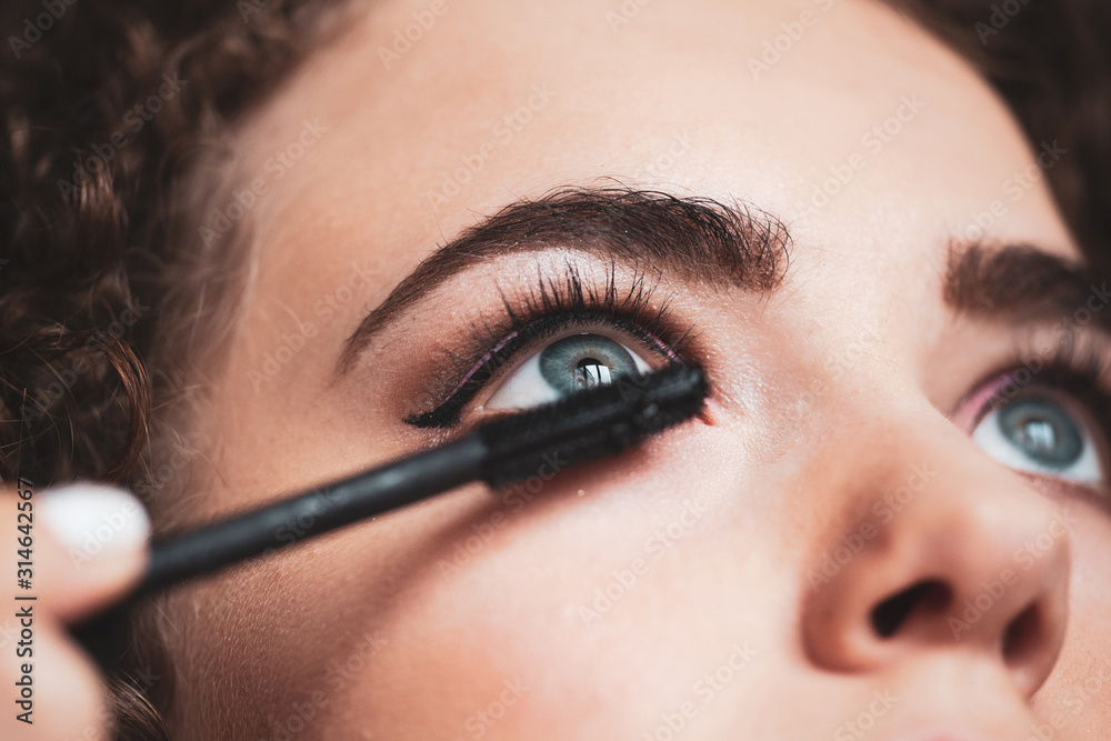 The work of a professional makeup artist. Closeup of makeup artist applying smokey eyes makeup. Eyelash extension procedure.