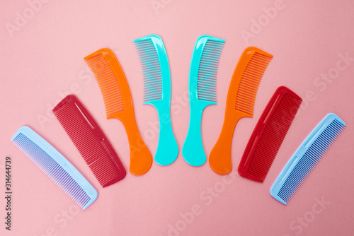 Various colored brushs and combs for hair on pink background. collection of combs