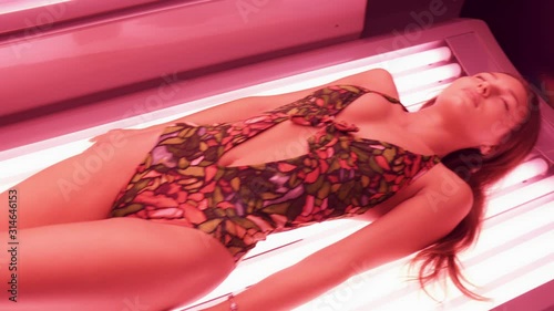 Beautiful girl in swimsuit lying and sunbathing in solarium