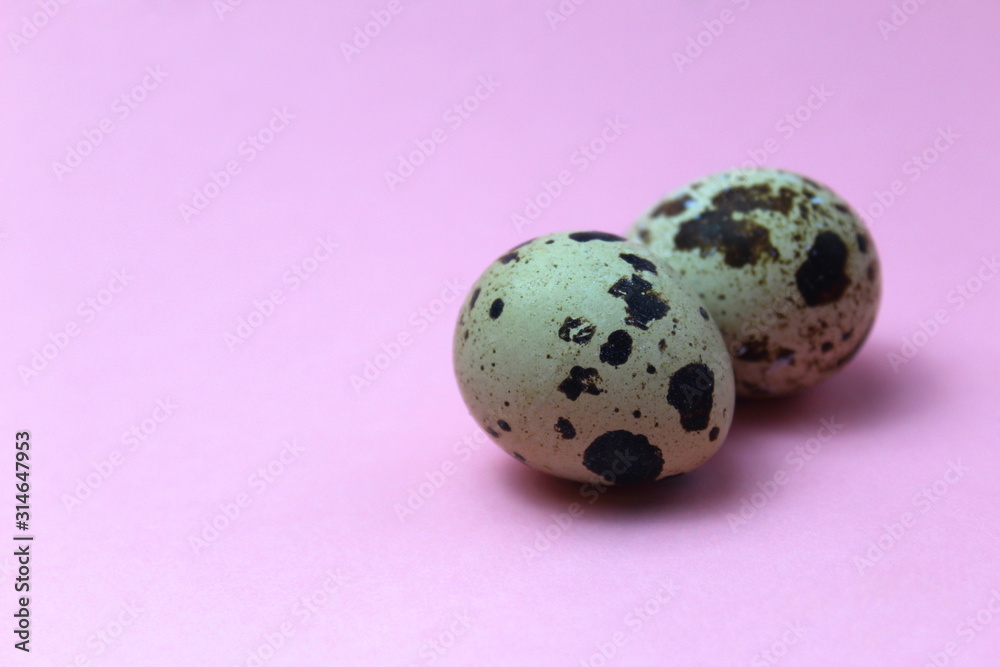 Two quail eggs lie on a pink background