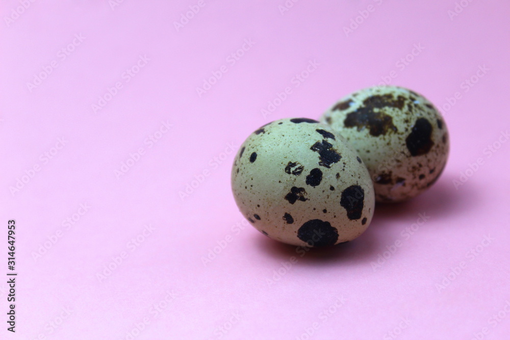 Obraz premium Two quail eggs lie on a pink background