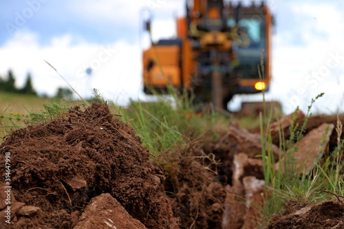  Soil on the Trench for a cable . CRAWLER EXCAVATOR Works on digging blurred