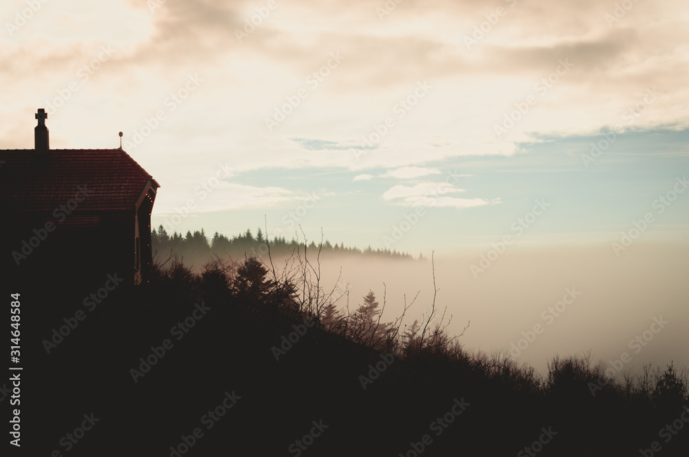 Lone building on the top of the mountain with deep fog underneath