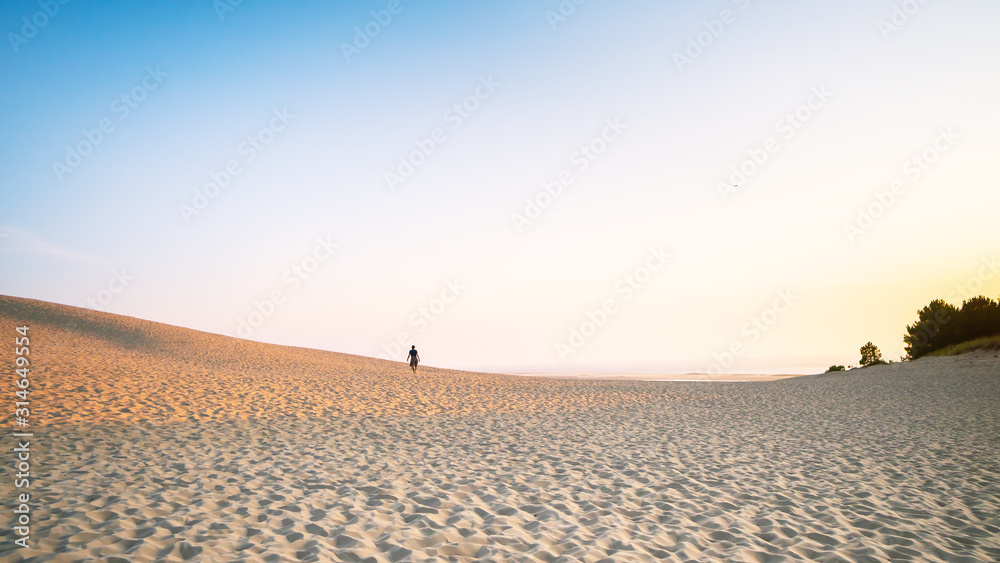 Sunset on the dune. Sand dune against the clear sky at sunset time, a lone traveler Sunset on the dune. Sand dune against the clear sky at sunset time, a lone traveler