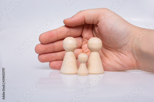 Hand protecting wooden figurines of people as family concept photo